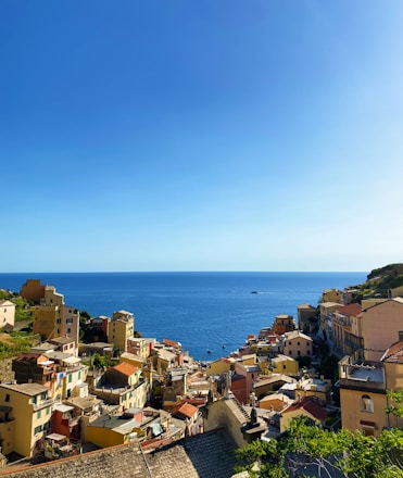 Coastal Mediterranean village with traditional houses and clear blue sea under sunny sky.