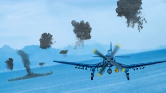 A dramatic shot of a WWII dive bomber releasing bombs over a distant target with smoke rising.