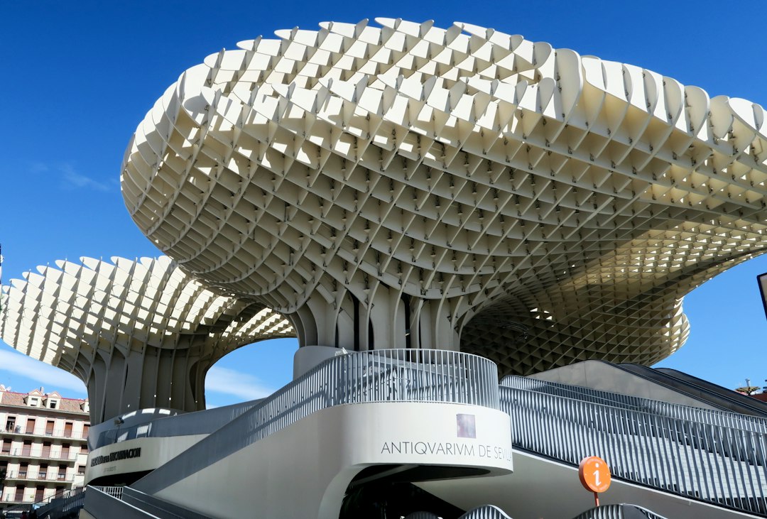 a large building with a curved roof with Metropol Parasol in the background