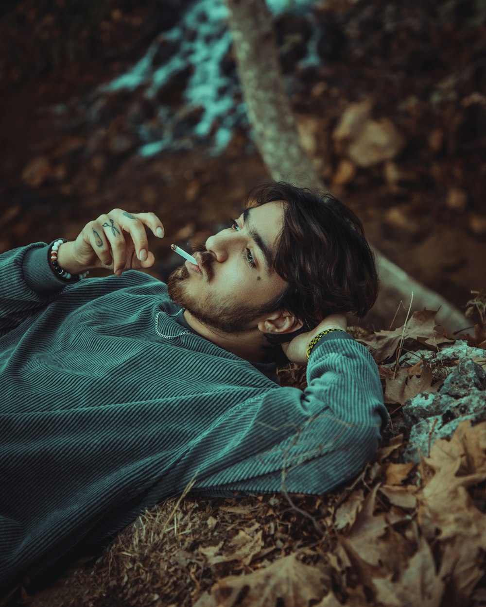 a person lying in the leaves smoking a cigarette