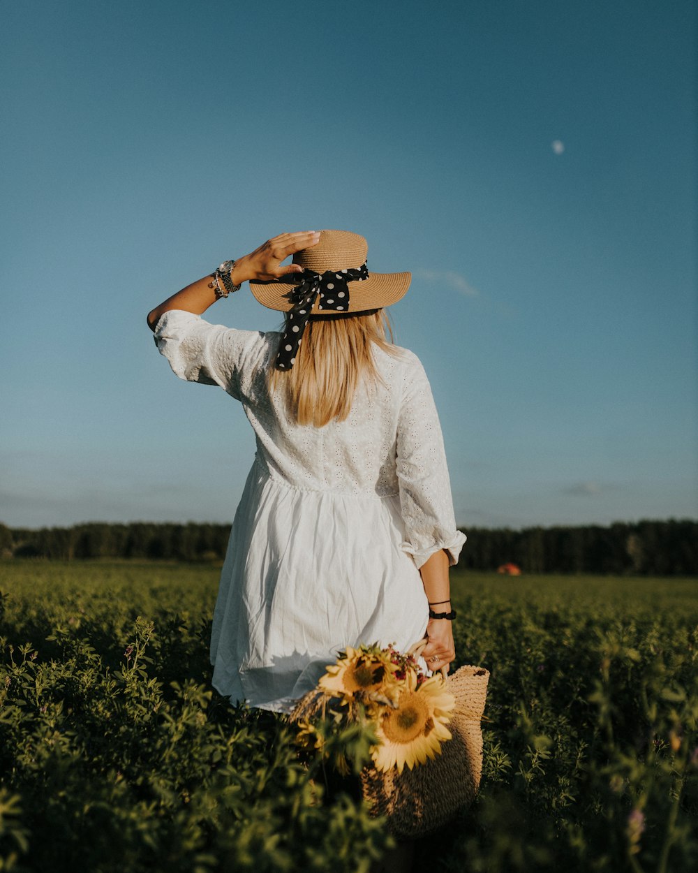 a person in a white dress holding flowers in a field