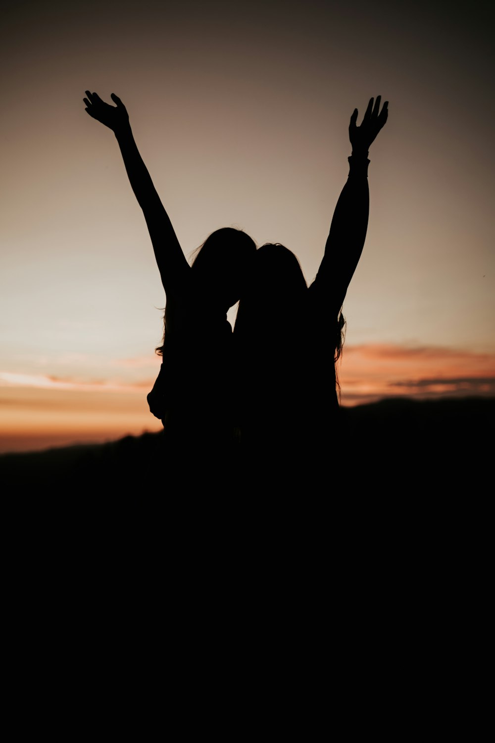 a silhouette of a woman and a man with their hands up