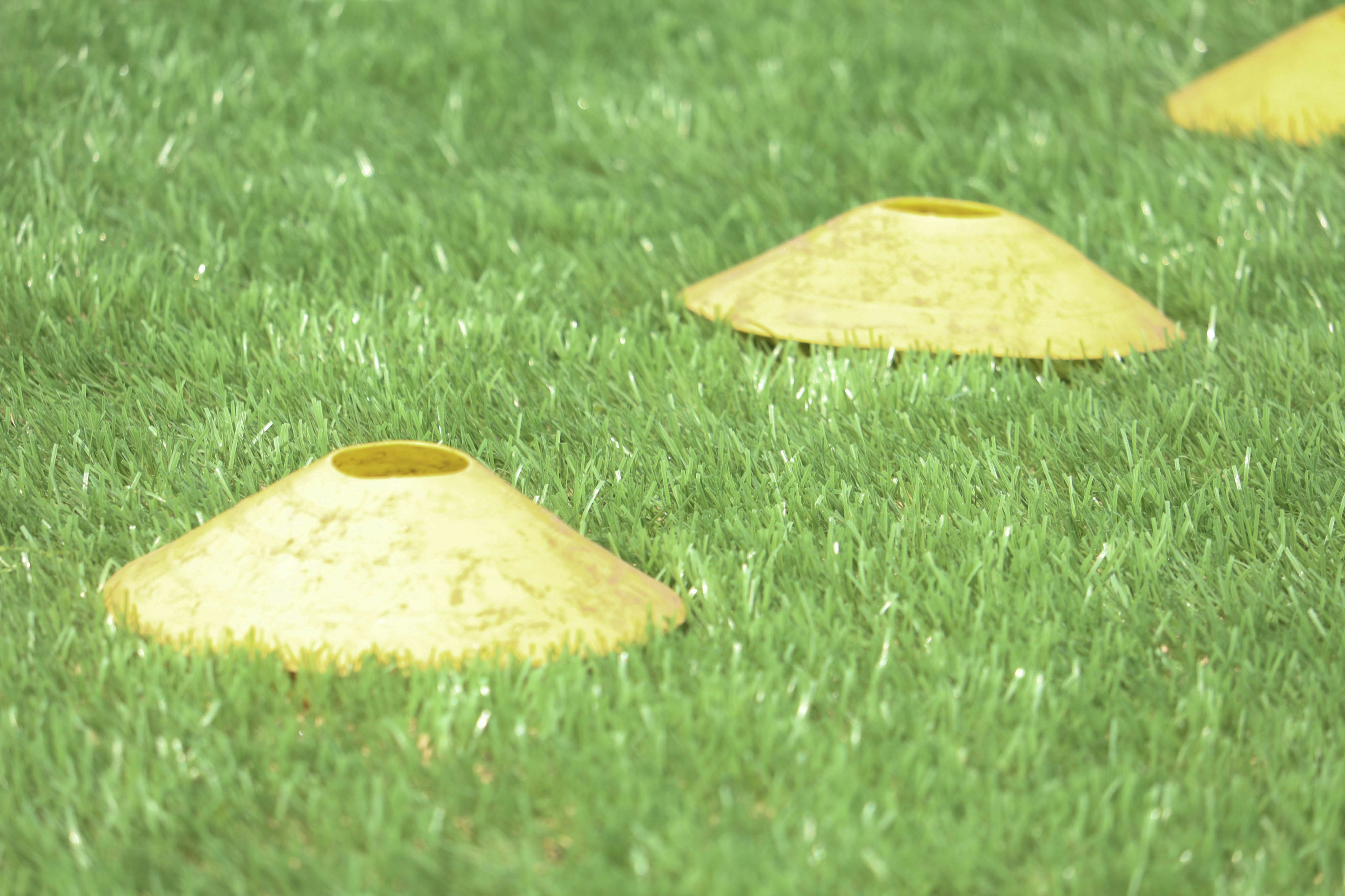 Kerucut latihan kuning berjajar di atas rumput hijau