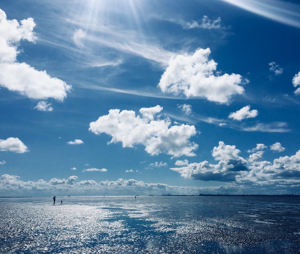 a body of water with people standing in it and a blue sky above