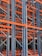 A complex structure composed of multiple metal beams and girders, mainly in dark blue and orange hues. The intricate, crisscrossing framework suggests the interior of an industrial racking system, possibly used for storage or support.