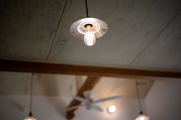 Close-up of a technician installing an industrial lighting fixture on a high ceiling.