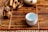 A small ceramic cup sits on a bamboo mat alongside a ceramic figurine resembling an animal. The arrangement includes tea utensils and a teapot, creating a serene and traditional tea setting.