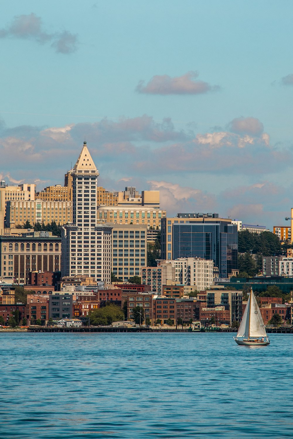 a sailboat in the water with a city in the background