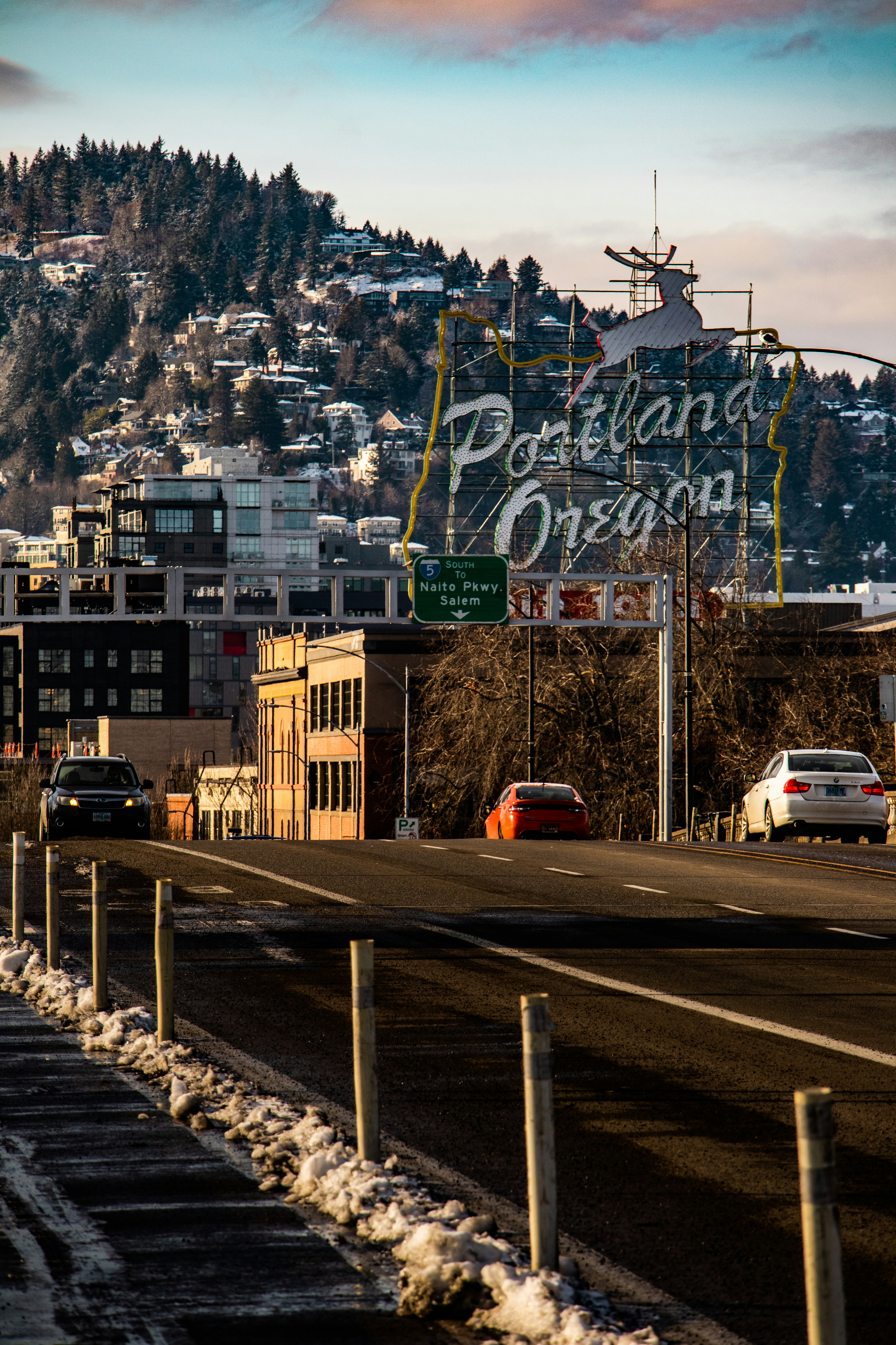a ferris wheel and a road with cars and buildings and a hill in the background