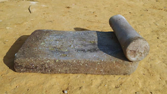 Hands grinding fresh spices with a traditional stone grinder in a rustic setting