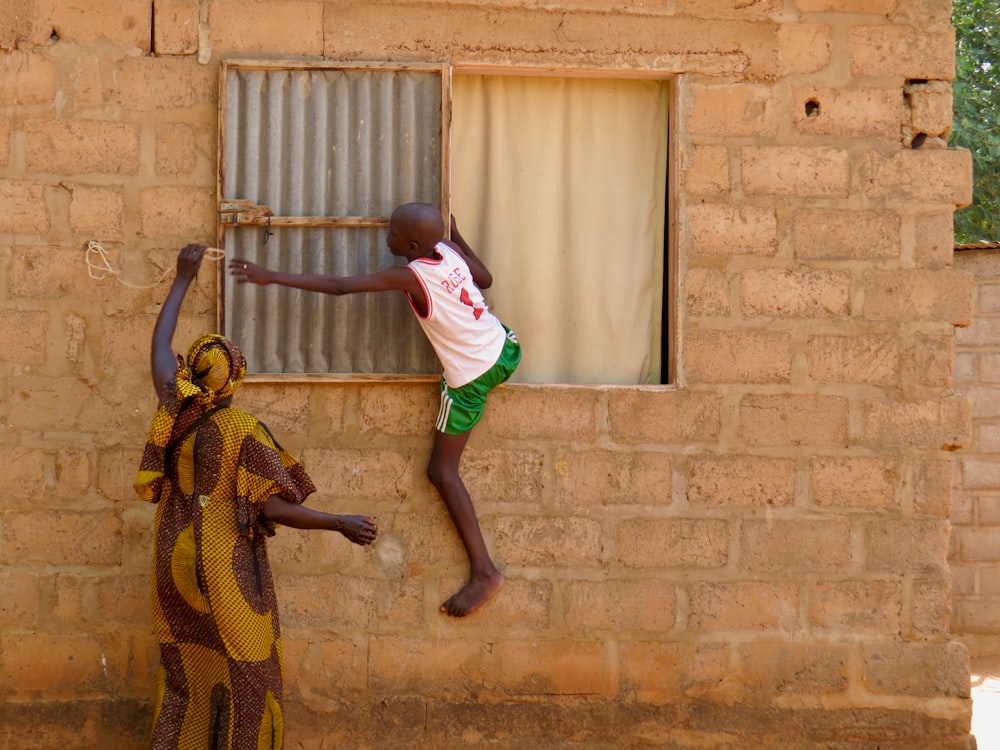 a boy jumping in the air with a person in a garment