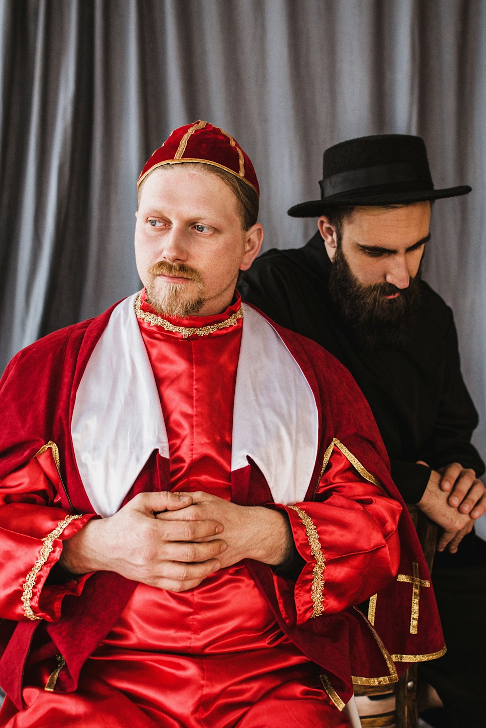 a man in a red robe and black hat with a man in a black robe and a black