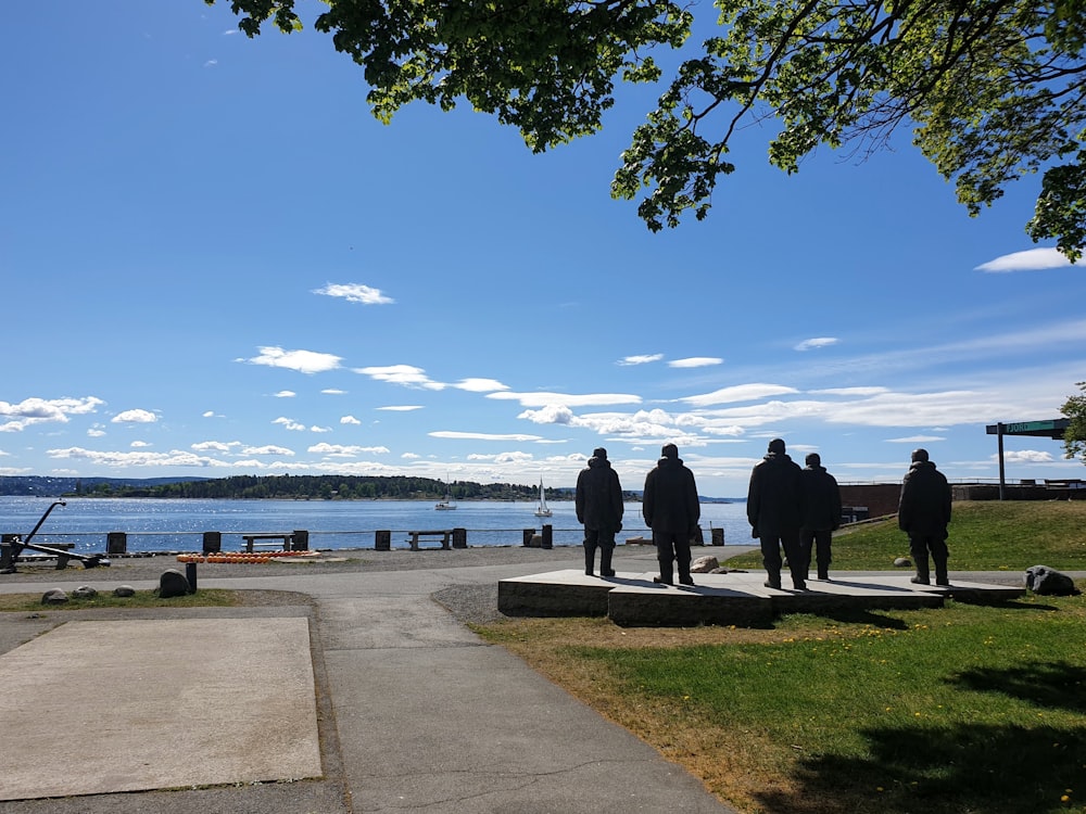 a group of people standing on a path by a body of water