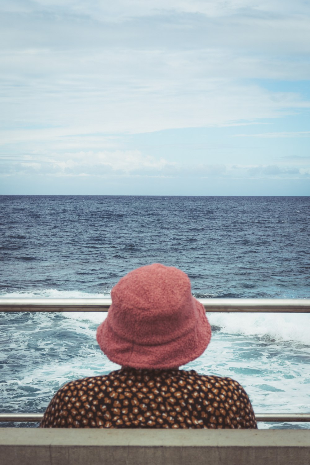 a hat on a railing overlooking the ocean