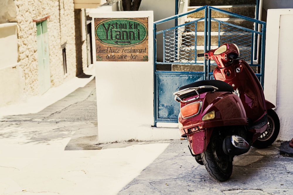 a red scooter parked on the sidewalk