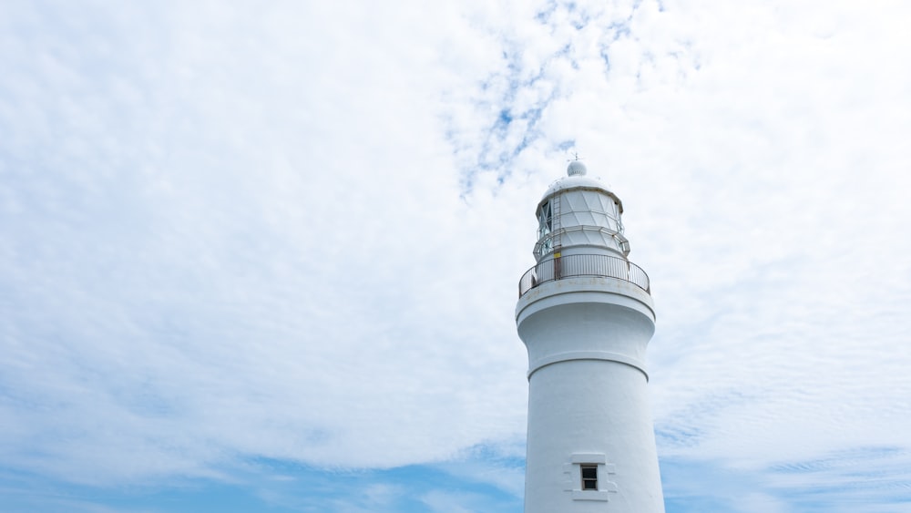 a white lighthouse with a cloudy sky