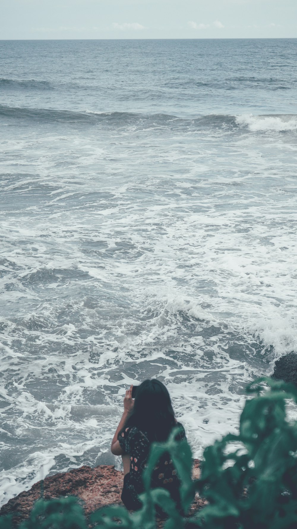 a man sitting on a rock by the ocean