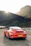 A sleek, vintage red Toyota AE86 parked on a scenic mountain road.