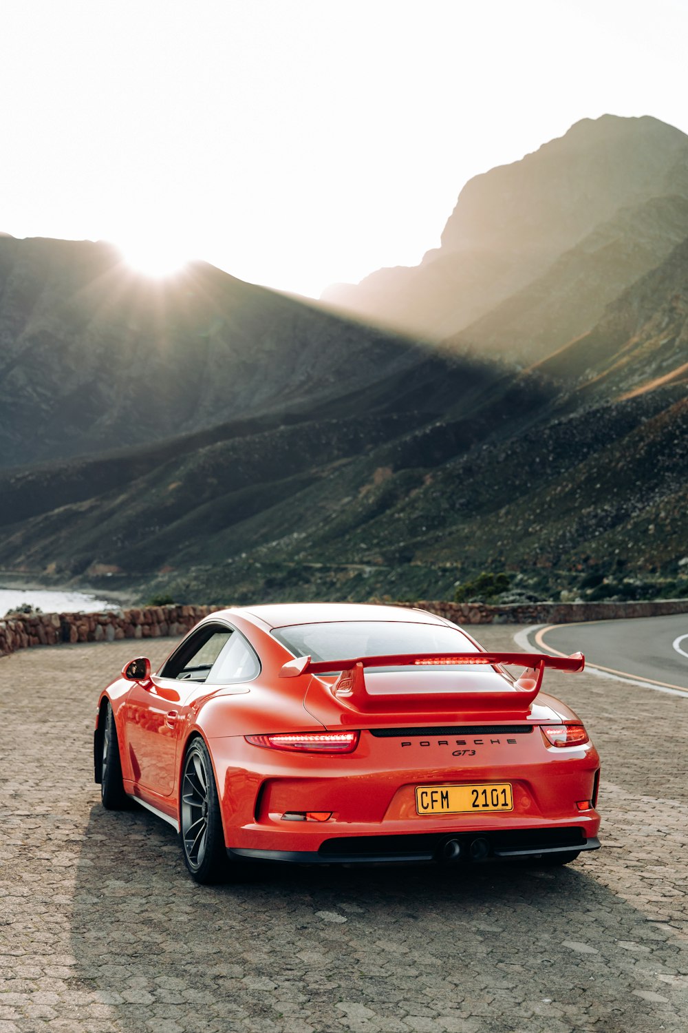 a red sports car on a road with mountains in the background