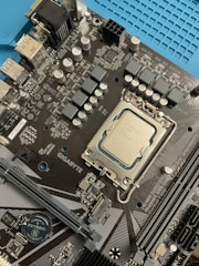 Technician repairing a computer motherboard with various hardware components around.