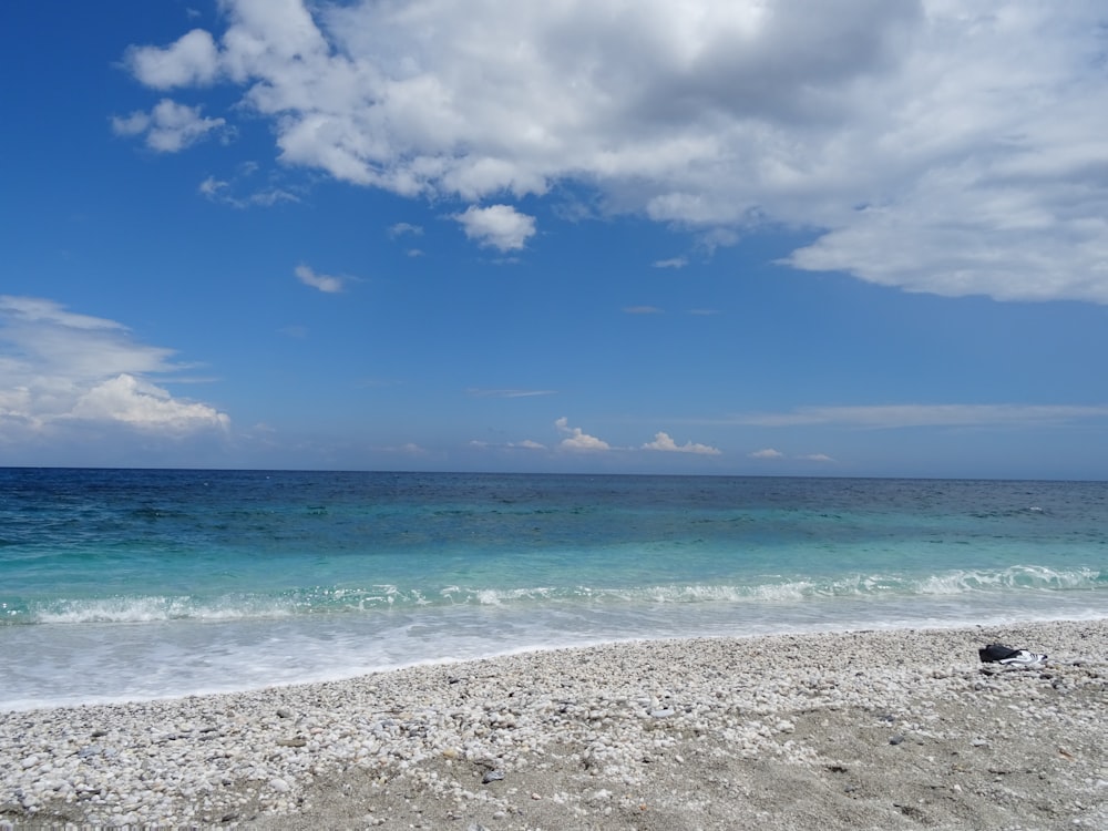 a beach with a body of water and clouds in the sky