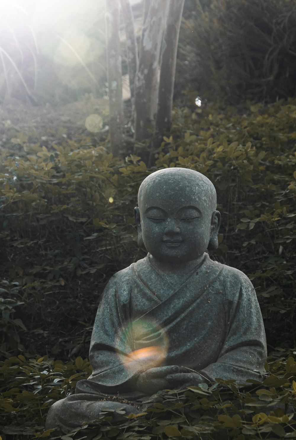 a statue of a person sitting in a forest