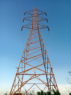 A high-voltage transmission tower standing tall against a clear blue sky, showcasing sturdy steel framework.