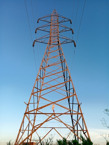 A high-voltage transmission tower standing tall against a clear blue sky, showcasing sturdy steel framework.