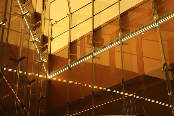 Architectural detail of intersecting glass panels with muted gold accents catching the light.