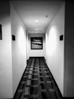 Before and after shots of a hallway transformed by expert plastering and painting.