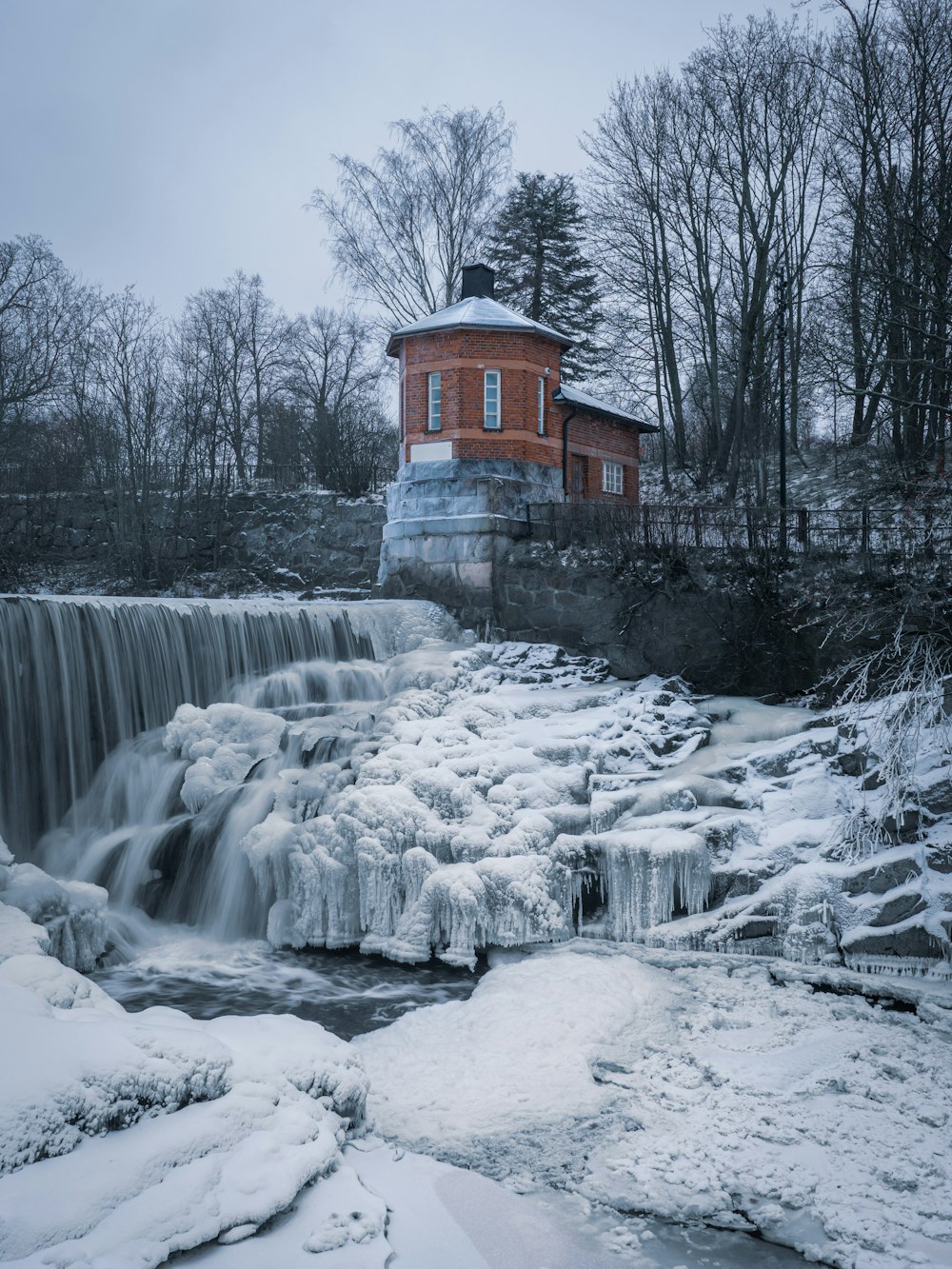a brick building with a waterfall and snow on the ground