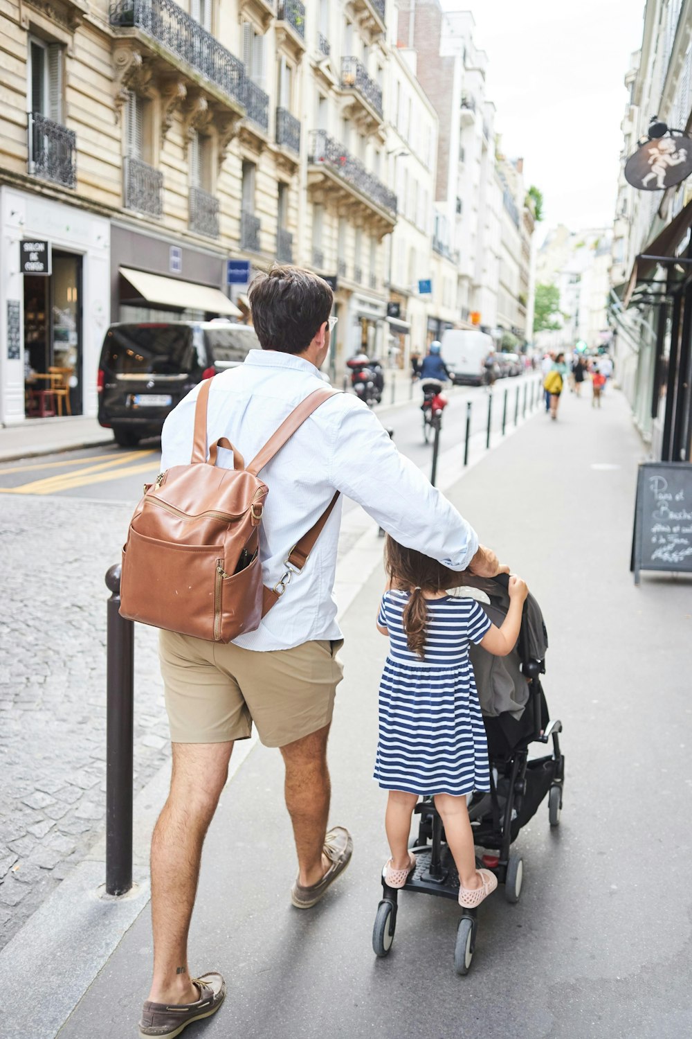 a man carrying a baby on a stroller on a city street