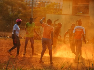 A lively snapshot of young athletes practicing football on a green field at Moohan Bagan Academy during sunset.