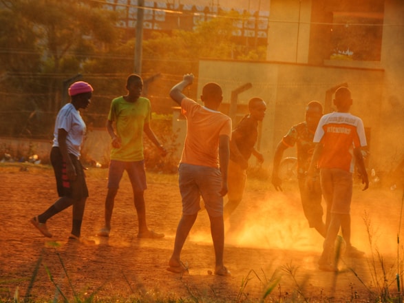 A group of teenagers energetically playing sports outdoors in a sunlit park.