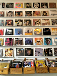 A colorful display of vintage 70's, 80's, and 90's vinyl records stacked and arranged on wooden shelves.