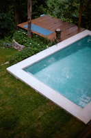 Piscina moderna com um toque natural, revestida com deck de madeira. 
