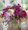 A vibrant bouquet of mixed seasonal flowers in a rustic vase on a wooden table.