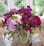 A vibrant bouquet of assorted flowers in a simple vase on a wooden table.