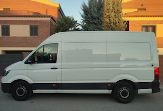 A delivery van parked outside a busy small business office in the early morning.