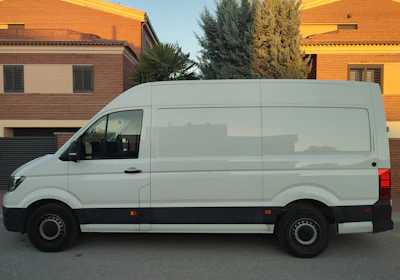 A delivery van parked outside a busy small business office in the early morning.