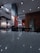 A modern fast-food restaurant interior features sleek lighting fixtures and wooden accents. The space includes tables and chairs arranged neatly. Wall decorations include a large logo and branded signage, creating a branded atmosphere.