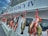 A row of freshly caught fish hanging from hooks on the side of a boat. The name 'CAPT. STACY IV' is prominently displayed on the boat's exterior. Several vibrant red ribbons secure the fish to the hooks, showcasing a variety of fish species against the vessel's white backdrop.