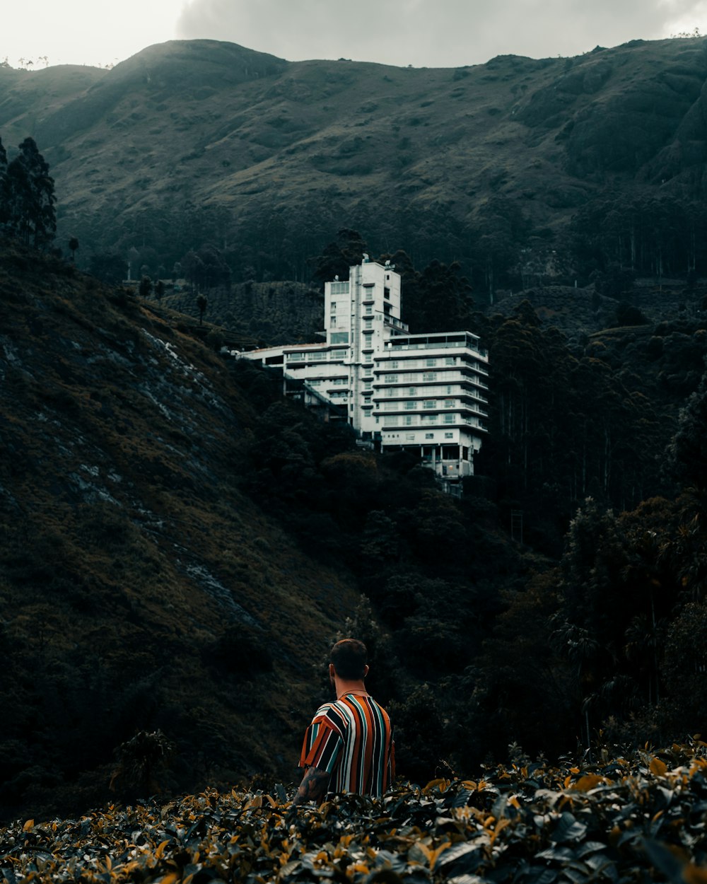 a person standing on a rocky hillside looking at a large white building