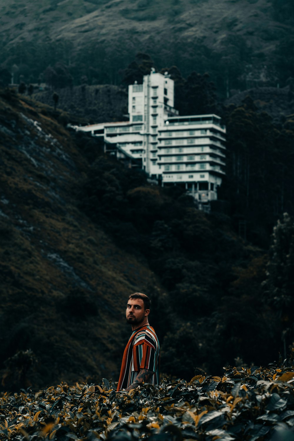 a man standing on a hill with a building in the background