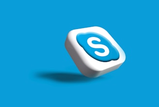 A 3D icon with the letter 'S' in white, encased in a blue cloud-like shape on a white square. It appears to be floating with a shadow cast below it, set against a solid blue background.