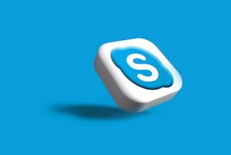 A 3D icon with the letter 'S' in white, encased in a blue cloud-like shape on a white square. It appears to be floating with a shadow cast below it, set against a solid blue background.