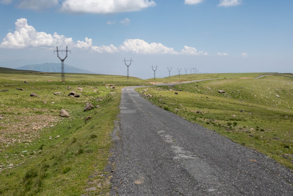 a road with grass and power lines on the side