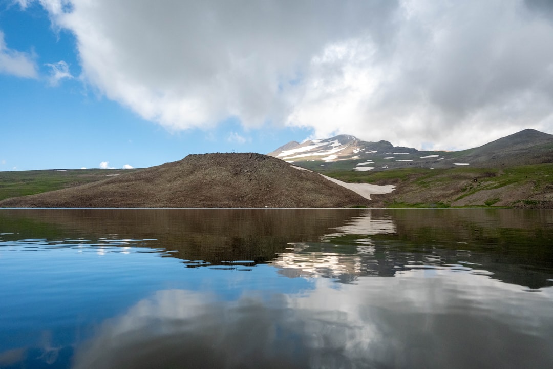 a body of water with hills in the background, Mount Aragats is reflected in the waters of Lake Kari.