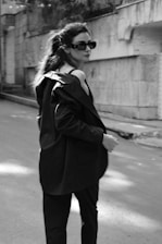 Elegant woman wearing a timeless tailored jacket blending classic and modern styles in a sunlit urban setting.