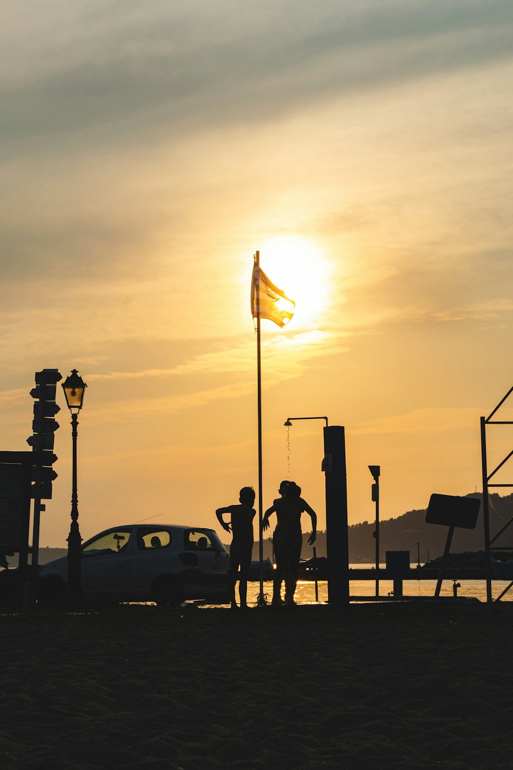 a couple of people standing on a dock with a flag and a car